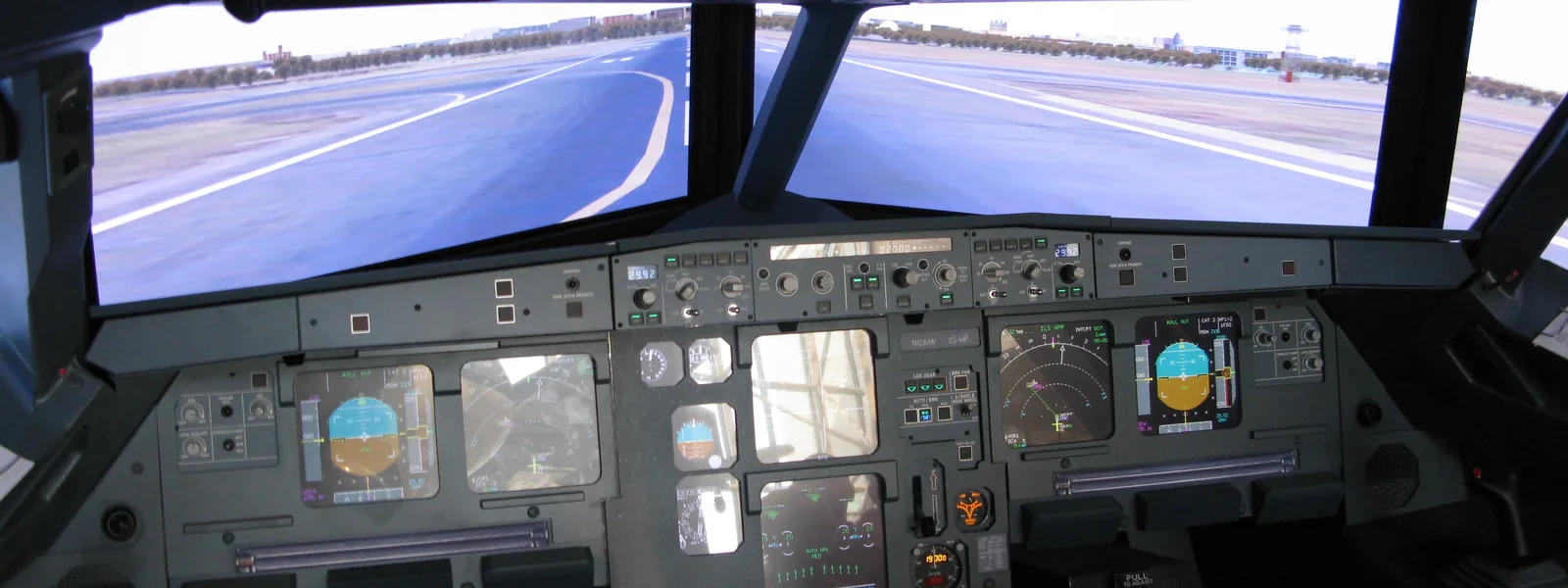 Airbus A320-family flight simulator cockpit with glass displays and a simulated runway view through the windscreen